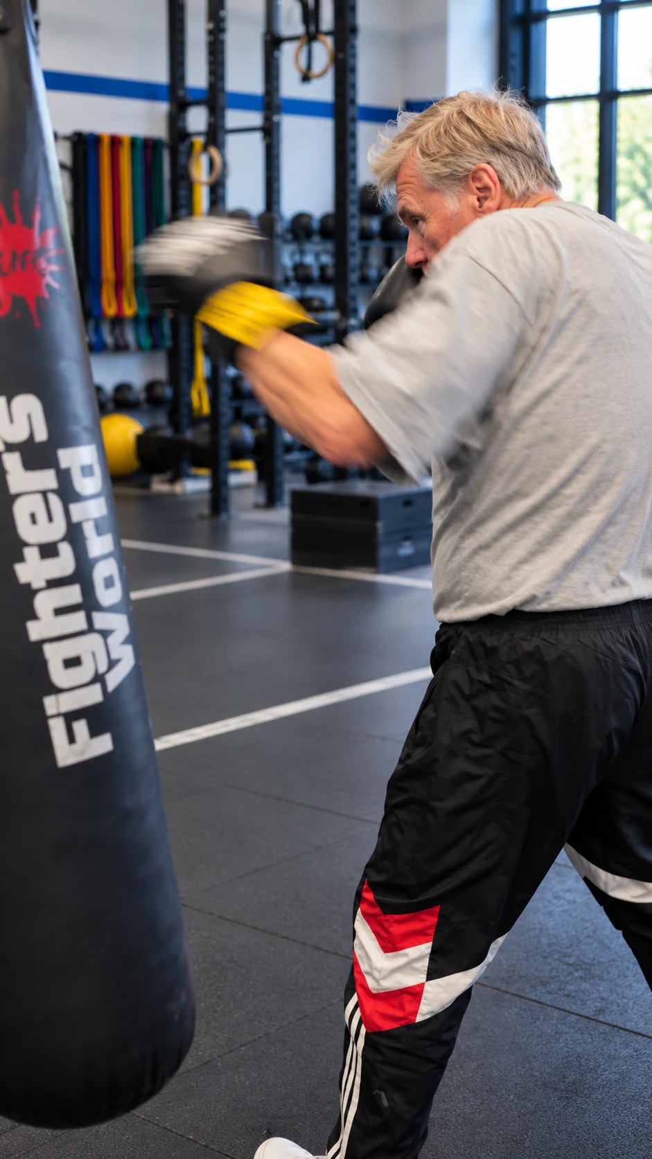 Ein älterer Mann trainiert mit Boxhandschuhen an einem Sandsack