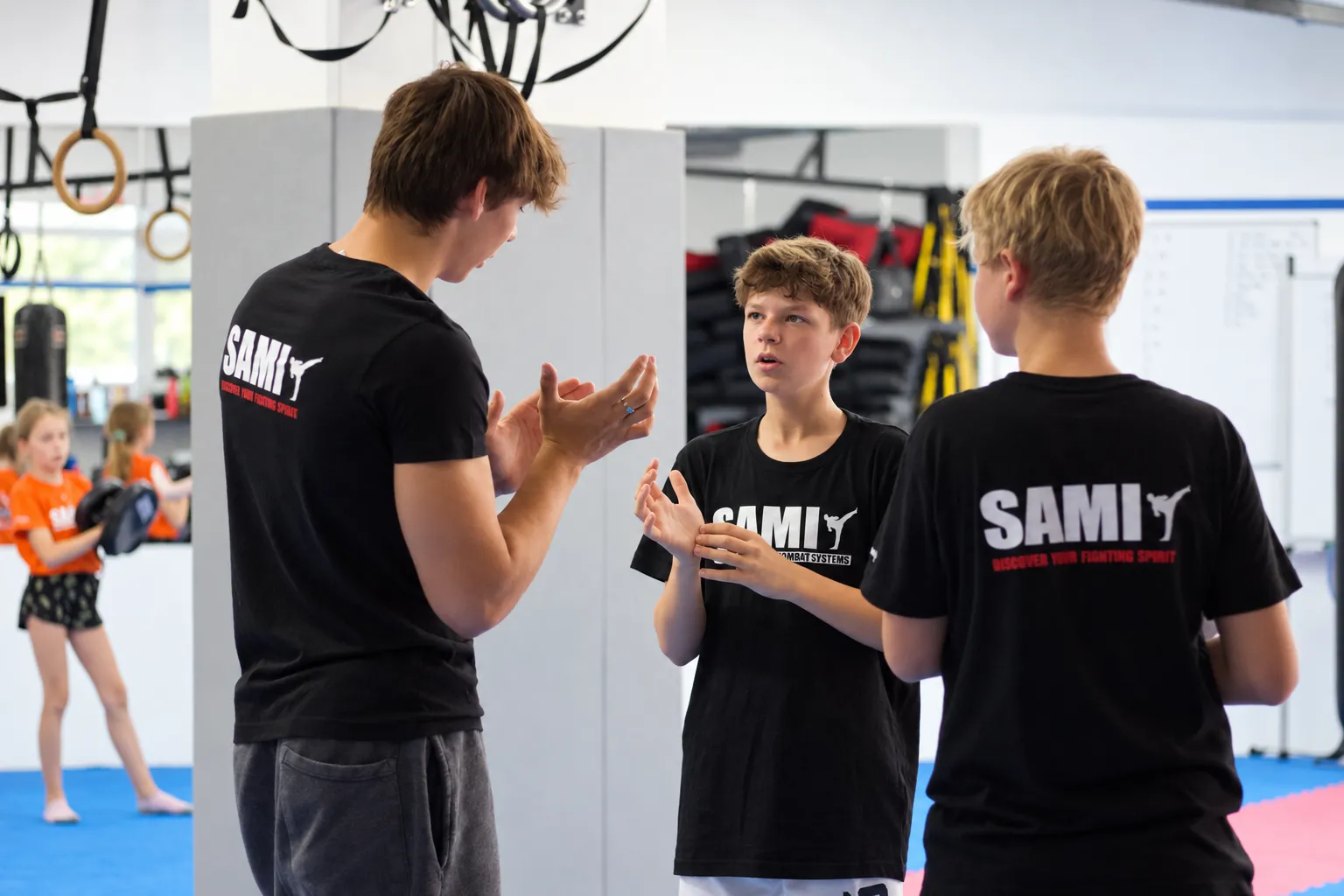 Ein Trainer erklärt zwei Jugendlichen eine Übung