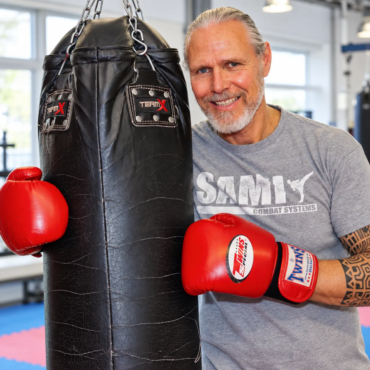 Trainer mit Boxhandschuhen neben einem Sandsack
